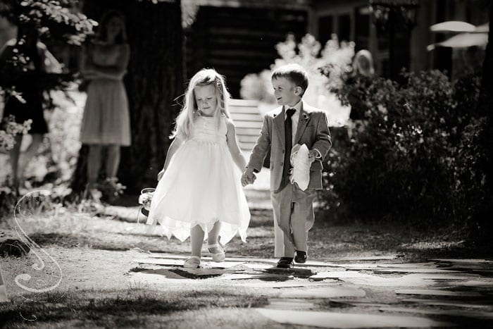 The flower girl and ring bearer walk down the aisle together during the ceremony.