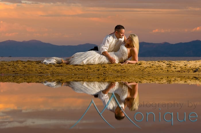 bride and groom laying in sand