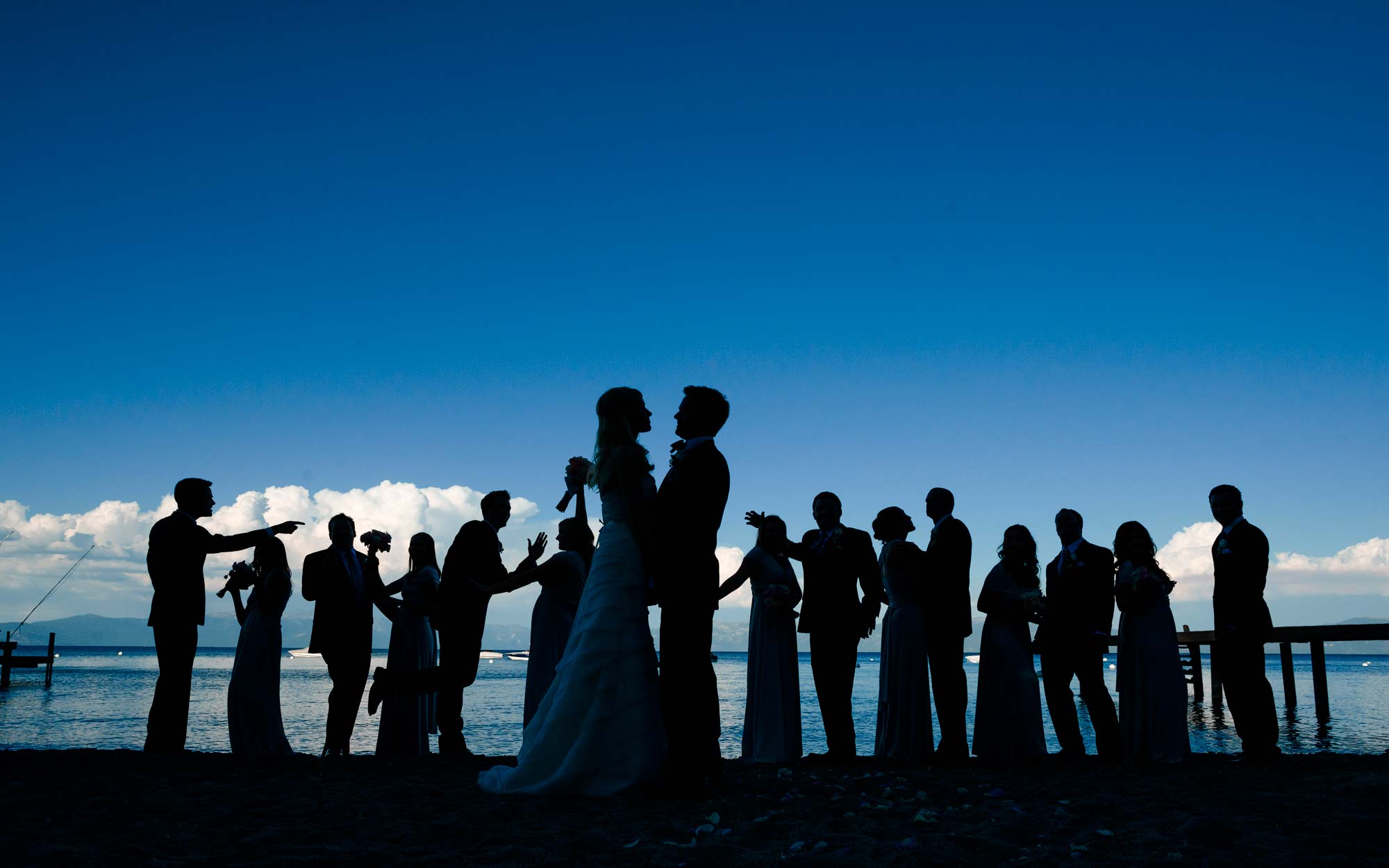 Photograph of silhouetted wedding party on the shore of Lake Tahoe during a Lake Tahoe private estate wedding. Photography by Monique, Lake Tahoe wedding photographer.