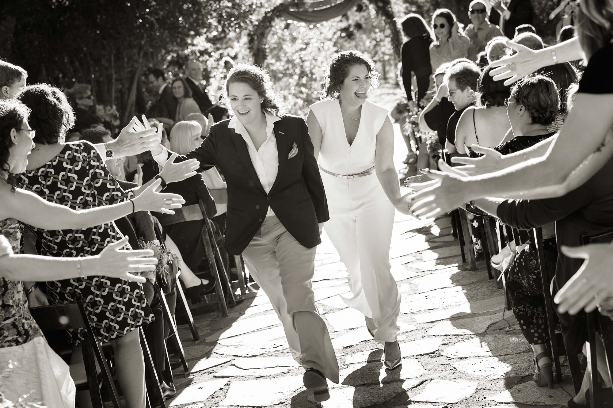 Photograph of same sex wedding in black and white of two brides happily walking down the aisle during their Plumpjack wedding in Squaw Valley, California. Image by Photography by Monique, Lake Tahoe wedding photographer.
