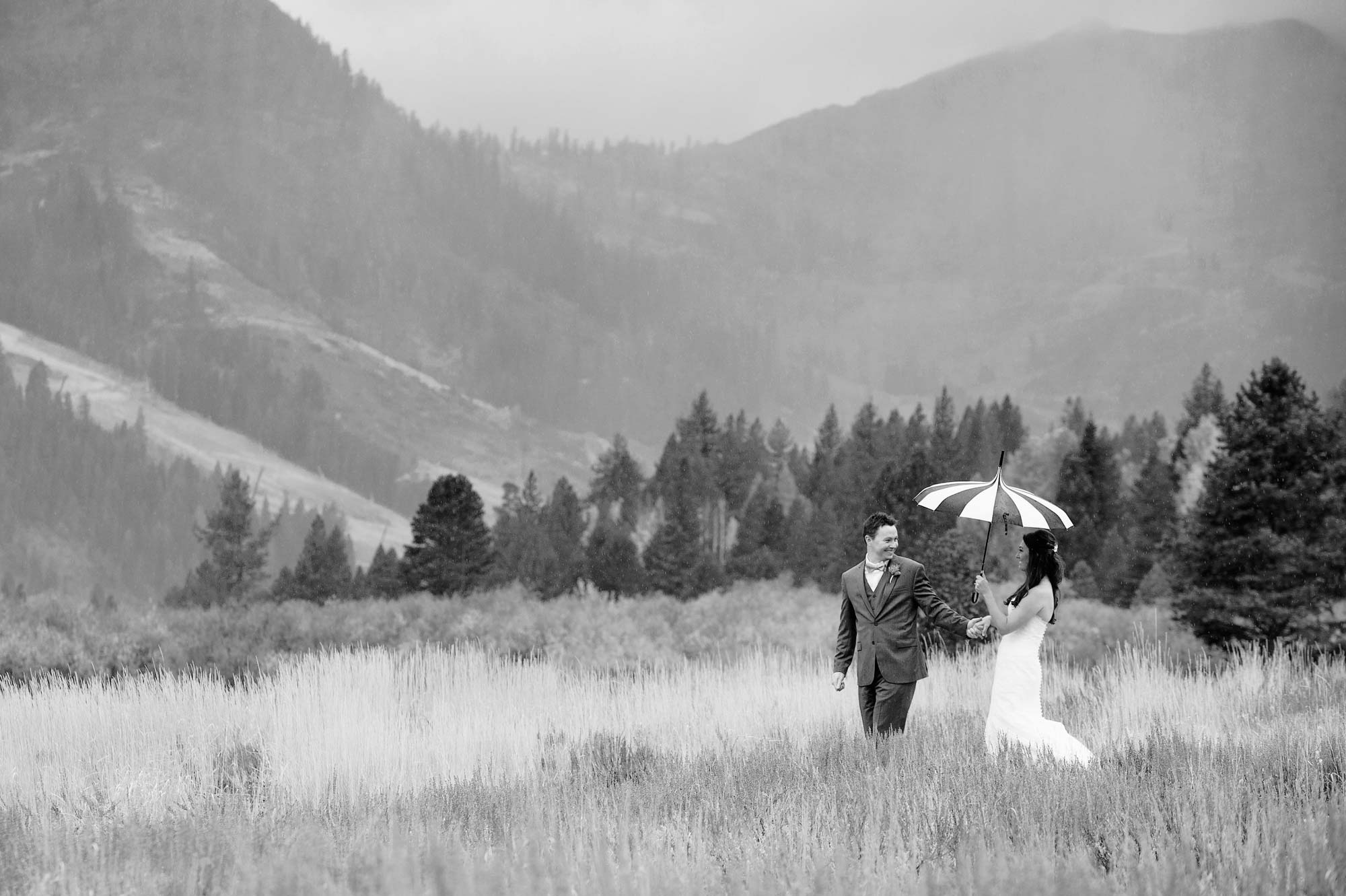 Squaw Valley, California wedding photography at the Resort at Squaw Creek. Picture of a bride and groom walking through the valley in a rainstorm taken by Photography by Monique, Lake Tahoe wedding photographer.