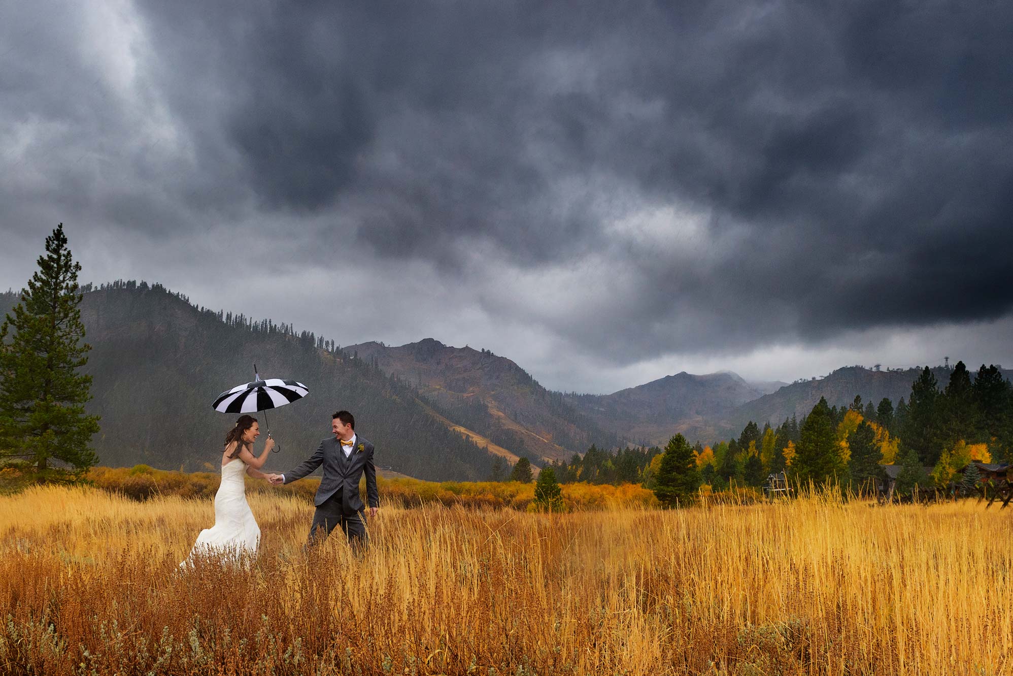 Squaw Valley wedding of bride and groom walking in meadow in rain storm