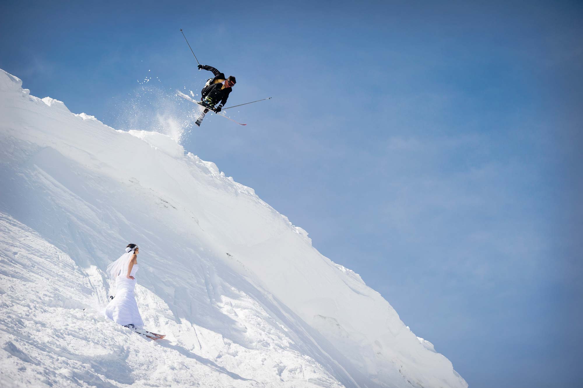 Groom jumping over bride while on Skis at Squaw Valley