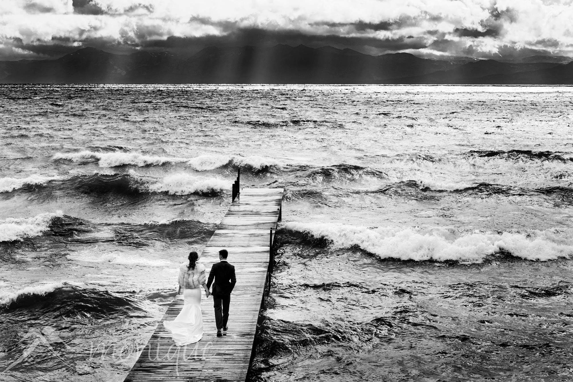 Lake Tahoe wedding photography with the bride and groom on a pier with waves crashing