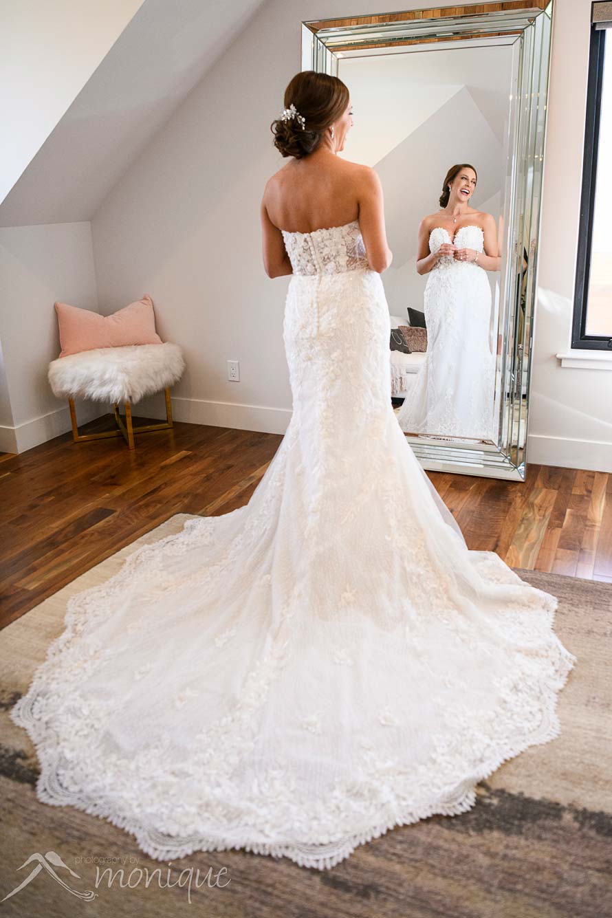 A bride looks in the full length mirror at the Elm Estate with the train of her dress spread out behind her
